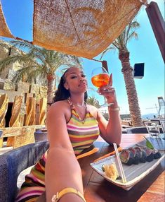 a woman sitting at a table with food and drink in front of her, under an umbrella