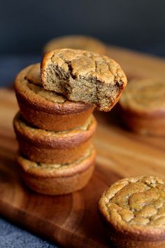 a stack of muffins sitting on top of a wooden cutting board next to each other