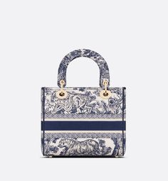 The Lady D-Lite bag combines classic elegance with House modernity. The style is fully embroidered with the blue Toile de Jouy motif. The front features a Christian Dior Paris signature while the thick D.I.O.R. charms in pale gold-finish metal enhance the silhouette. Equipped with a wide, reversible and removable embroidered shoulder strap, the medium Lady D-Lite bag can be carried by hand or worn crossbody.. Elegant Top Handle Shoulder Bag With Embroidered Logo, Designer Embroidered Top Handle Bag, Elegant Double Handle Bag With Embroidered Logo, Luxury Embroidered Top Handle Shoulder Bag, Luxury Shoulder Bag With Embroidered Logo And Top Handle, Luxury Shoulder Bag With Embroidered Logo For Daily Use, Elegant Bags With Embroidered Logo For Everyday Use, Luxury Blue Bag With Embroidered Logo, Luxury Blue Bags With Embroidered Logo