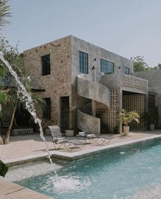 a house with a pool in front of it and a waterfall coming out of the back