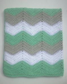 a green and white crocheted blanket sitting on top of a table