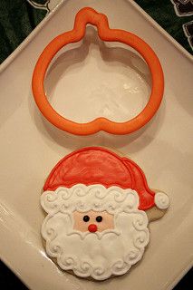 a cookie shaped like santa claus on a white plate with an orange ring in the middle