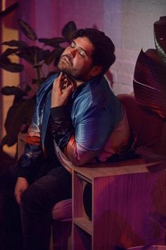 a man sitting on top of a wooden table next to a plant