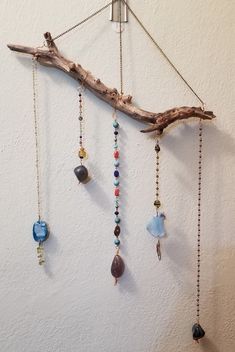 a branch with beads hanging from it on the wall next to a white wall and another piece of driftwood