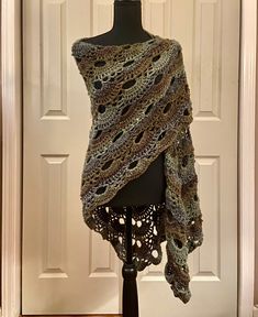 a crocheted shawl draped over a mannequin's head in front of a door