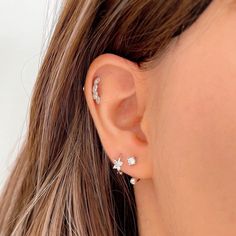 a close up of a woman's ear with three small white flowers on it