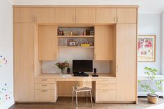 a desk with a computer on top of it in front of a wall mounted cabinet