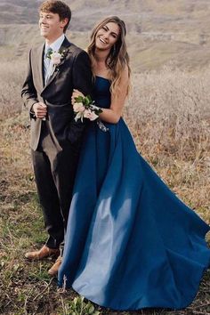 a man and woman in formal wear standing next to each other on a hill side