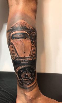 a man with a tattoo on his leg that has a car and mountains in the background