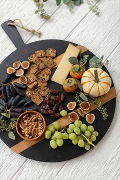 a black plate topped with different types of food and fruit on top of a wooden table