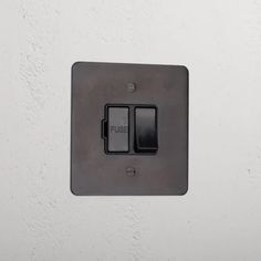 a black light switch sitting on top of a white wall