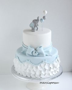 a blue and white cake with an elephant topper sitting on it's side