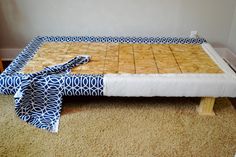 a bed that is made out of plywood and has a blanket on top of it