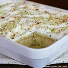 a white casserole dish filled with food on top of a wooden table next to a napkin