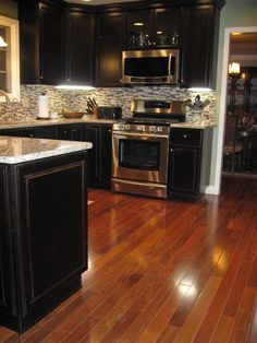 a kitchen with wood floors and stainless steel appliances