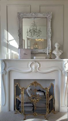 a white fireplace with a mirror above it and a chandelier on the mantle