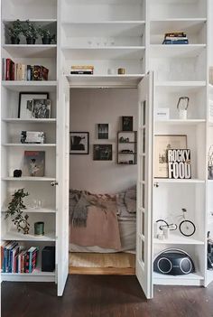 an open bookcase in the corner of a room filled with books and other items