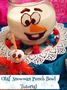 a snowman punch bowl is sitting on top of a doily with beads and candy