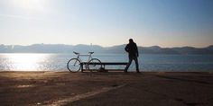 a person standing next to a bike near the water