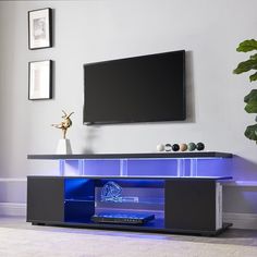 an entertainment center with blue lights and a flat screen tv mounted on the wall above it