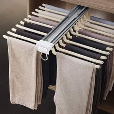 a rack with towels hanging from it in front of a wooden cabinet filled with clothes