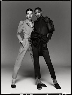 two women standing next to each other in front of a black and white background,