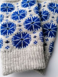 two blue and white knitted mittens sitting next to each other