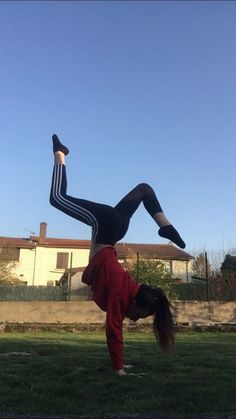 a woman doing a handstand in the grass