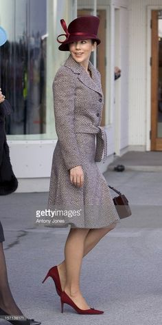 a woman in a coat and hat is walking down the street