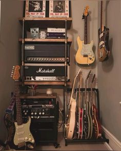 guitars and amps are lined up on a shelf in a room with gray walls