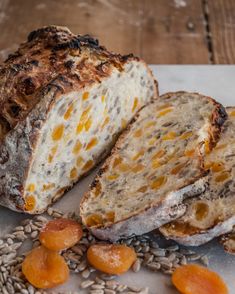 a loaf of bread sitting on top of a table next to oranges and seeds