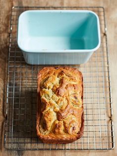 a loaf of bread sitting on top of a cooling rack next to a blue bowl