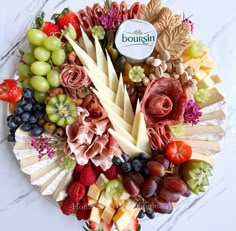 an assortment of cheeses and fruits arranged in a circular arrangement on a marble surface