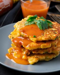 a stack of pancakes covered in sauce and garnished with parsley on a plate