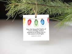 a christmas ornament hanging from a pine tree with a quote on it that reads, may the beautiful lights of every holiday season remind so as if