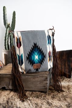 The perfect combination of tooled leather and saddle blanket Aztec pattern. Has long wide fringe detail with tooled leather top patch. Comes with tooled leather crossbody purse strap. Is fully lined with two inner side pockets as well as an inner zipper privacy pocket. Zipper top closure. Concealed Weapons CarrierMeasures: 15” x 14.5” Saddle Blanket Purse, Wide Fringe, Western Bags Purses, Purse With Fringe, Blanket Purse, Western Bag, Cowgirl Accessories, Southern Outfits, Country Style Outfits