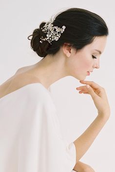 a woman in a white dress with a hair comb on her head and hands behind her back