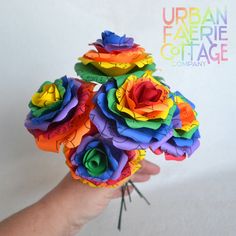 there is a hand that has some flowers made out of paper on it and the words urban faerie cottage company