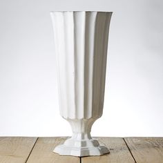 a white vase sitting on top of a wooden table