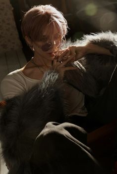 a woman sitting in a chair with her hands on the back of a dog's head