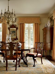 a formal dining room with chandelier, chairs and table in front of windows