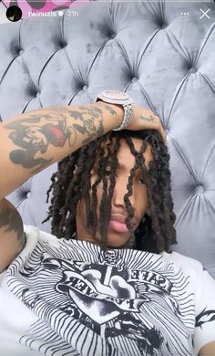 a man with dreadlocks sitting on top of a couch wearing a white shirt