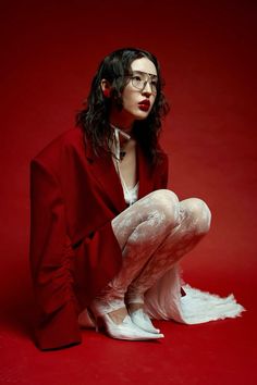 a woman with long hair and glasses is sitting on the floor wearing white tights