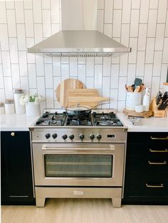 a stove top oven sitting inside of a kitchen next to a wooden cutting board and utensils