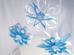 two blue and white paper flowers sitting on top of a table next to each other