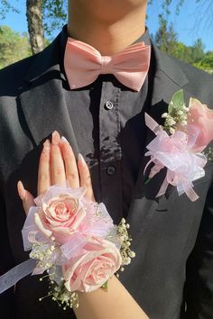 a man in a tuxedo and pink flowers holding his hands out to the camera