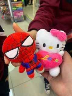 hello kitty and spiderman stuffed animals are being held by someone