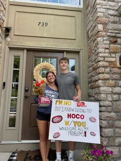 two people standing in front of a door holding signs