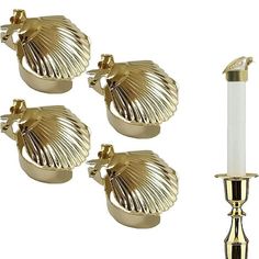 three gold candlesticks are next to each other and one candle holder is in the shape of a shell