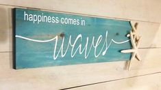 a sign that says happiness comes in waves on the side of a wooden plank wall